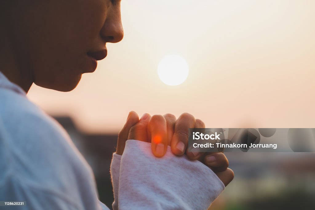 Woman praying in the morning on the sunrise background. Christianity concept. Pray background. Faith hope love concept. Praying Stock Photo