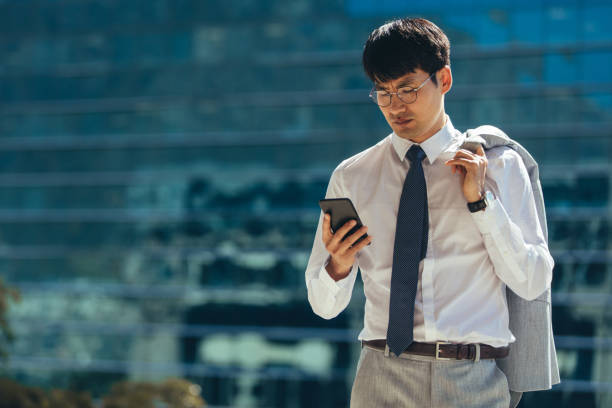 istock Businessman walking outdoors using his smart phone 1128627075