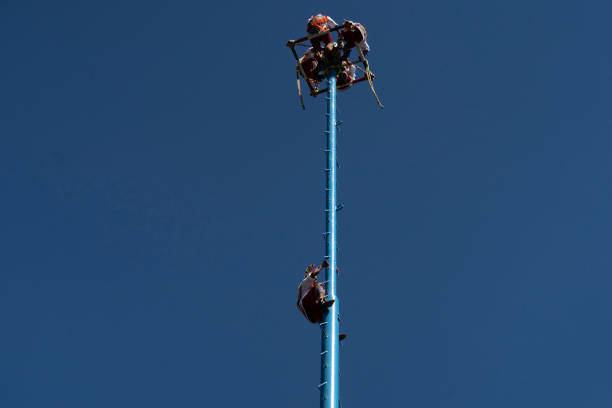 MEXICO CITY, MEXICO - JANUARY 30 2019 - The dance of flyers los voladores is an ancient Mesoamerican ritual still performed today to ask the gods to end a severe drought.\nThe ritual consists of dance and the climbing of a 30-meter pole from which four of the five participants then launch themselves tied with ropes to descend to the ground. The fifth remains on top of the pole, dancing and playing a flute and drum.