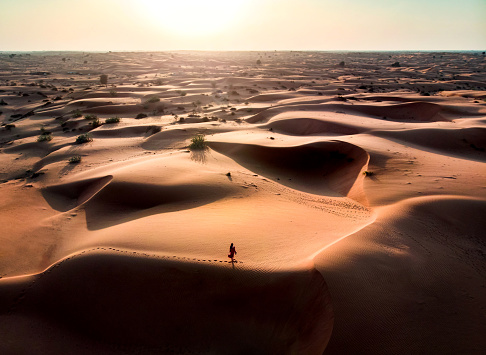 Woman walking in the desert during sunset aerial view