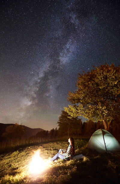 istock Woman resting at camp and tent under under night starry sky 1128633211