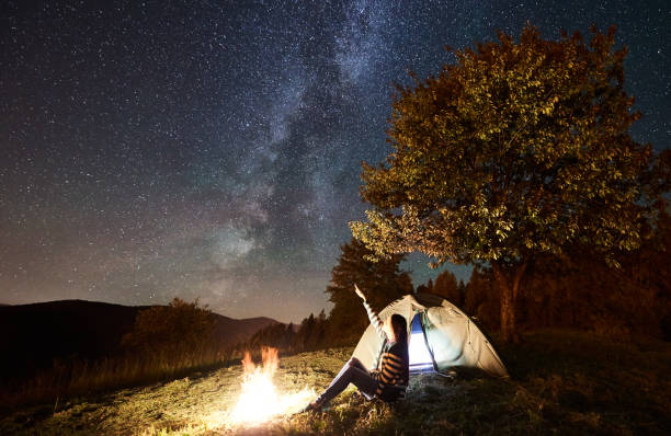 istock Woman resting at camp and tent under under night starry sky 1128633214