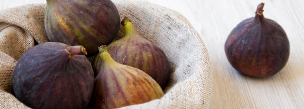 istock Fresh figs in a bowl on a white wooden background, side view. Closeup. 1128634206