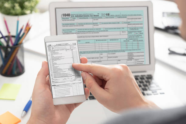 man filling tax information using mobile devices - tax tax form refund financial advisor imagens e fotografias de stock