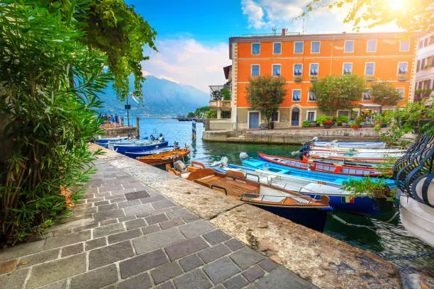 Stunning summer landscape, wooden fishing boats and colorful mediterranean buildings in spectacular harbor, Limone sul Garda tourist resort, lake Garda, Lombardy region, Italy, Europe