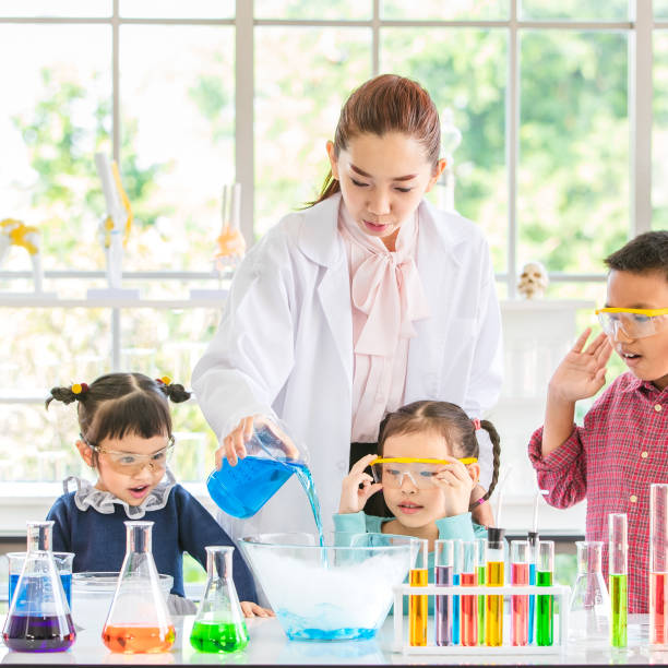 istock Teacher pour chemicals into glass bowl in lab. 1128636949