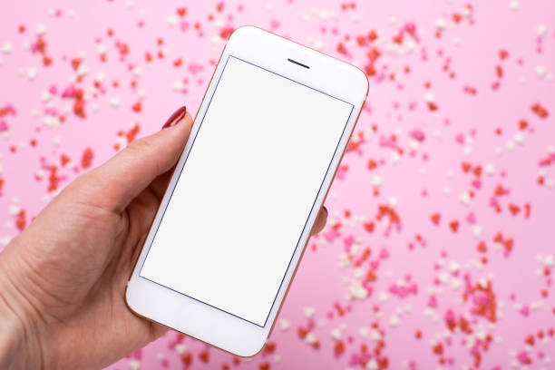 istock Female hand with mobile phone on background with pink and red hearts 1128637232