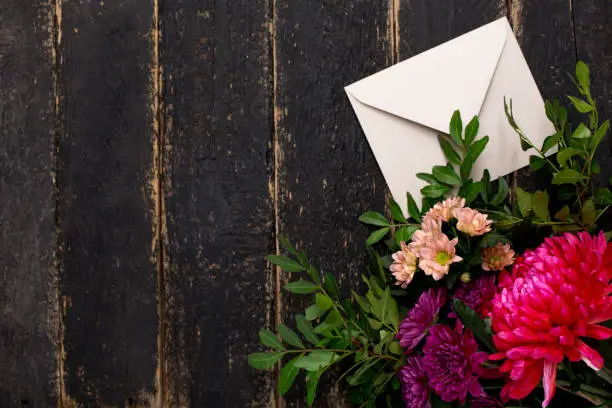 Photo of Envelope with a bouquet of flowers on a dark vintage wooden background