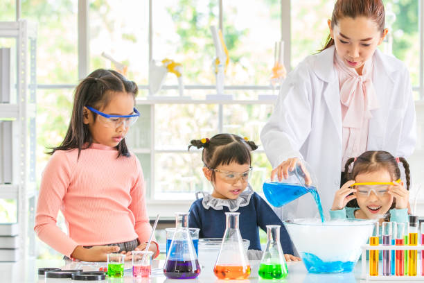 istock Teacher pour chemicals into glass bowl in lab. 1128637382