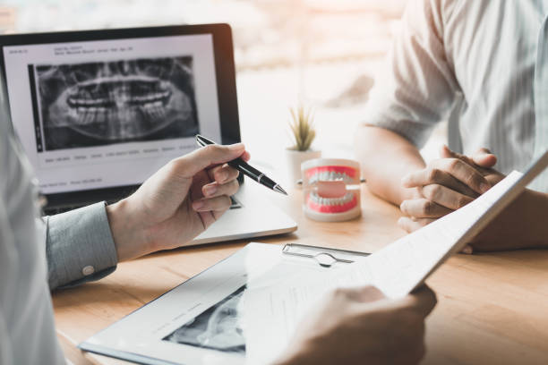 asiatische junge zahnärzte sind über die zahnwurzel behandlung von patienten im büro erklären. - laboratory dentures dental hygiene human teeth stock-fotos und bilder