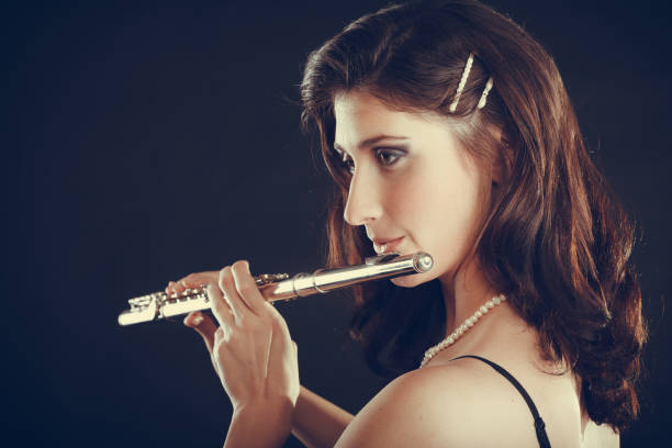 istock Woman playing transverse flute on black. 1128637710