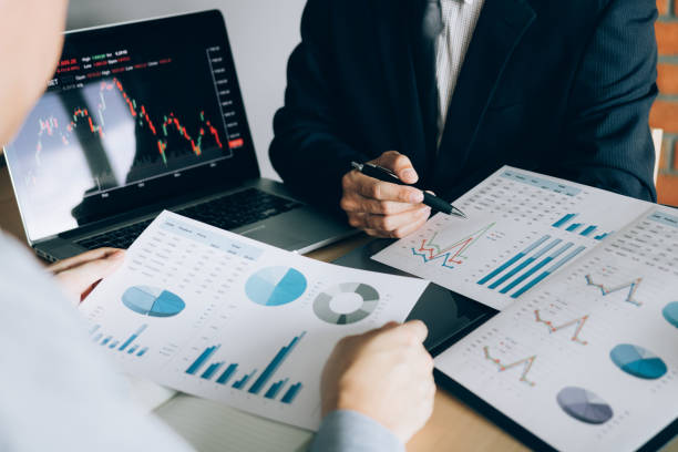 istock Two investors are working together with analyzing the stock data graphs in the paper and viewing the data on the laptop screen. 1128637721