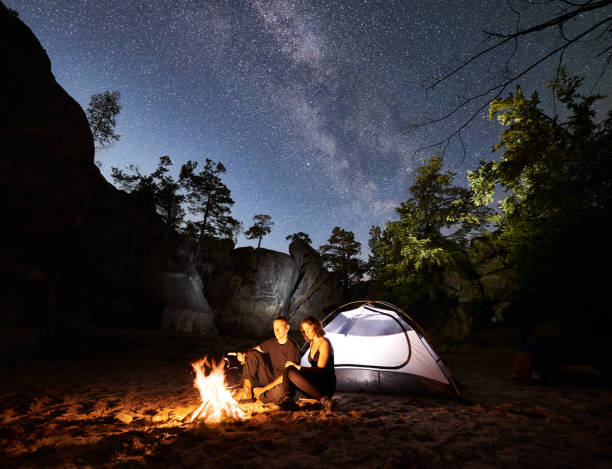 istock Couple tourists resting beside camp, campfire tent at night 1128638640