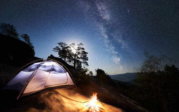 istock Tourist camping on rocky mountain under night starry sky 1128638660