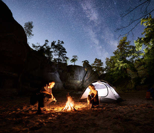 istock Couple tourists resting beside camp, campfire tent at night 1128638662