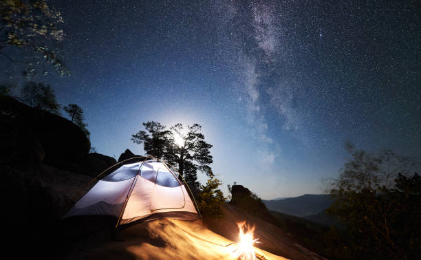 istock Tourist camping on rocky mountain under night starry sky 1128638663