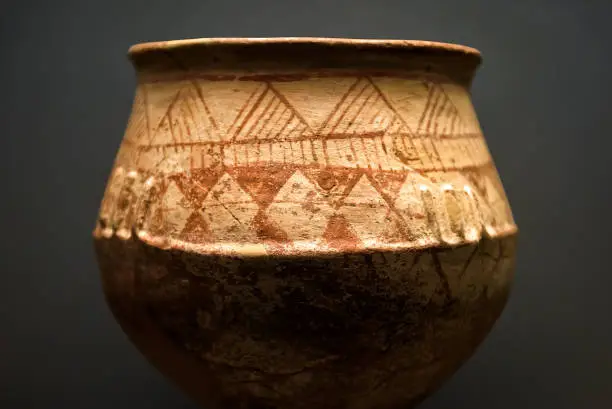 Ancient terracotta pot from the excavations in Greece. Painted archeological pottery. Remains of Ancient Greek culture. Antique ceramic with ornament. Old Greek patterned pottery on dark background.