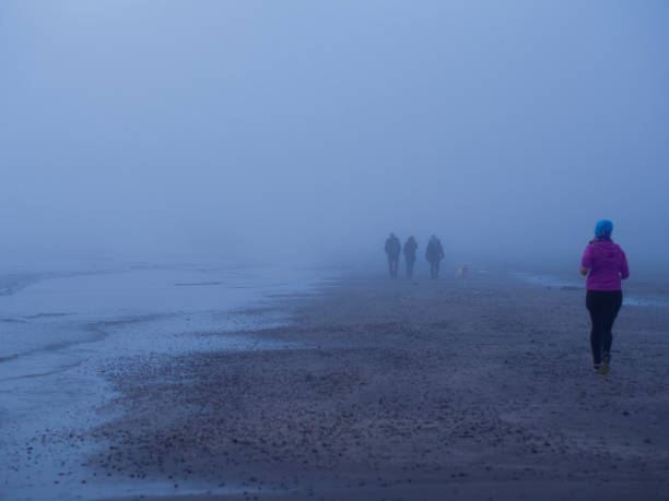 sur une plage de la mer du nord brumeuse - distance running jogging running fog photos et images de collection