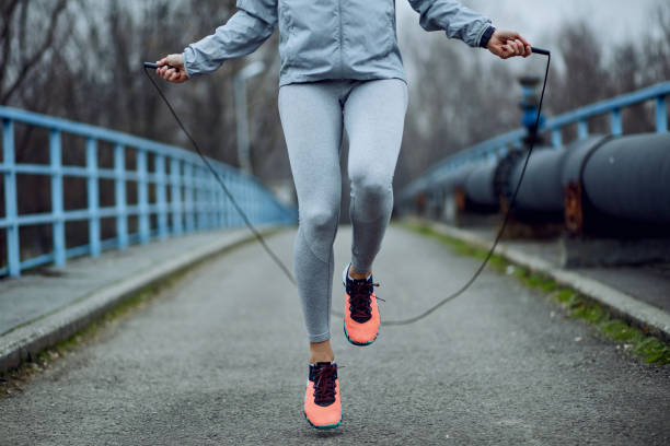 Unrecognizable sportswoman jumping rope on a bridge. Unrecognizable female athlete exercising with jump rope while having a sports training outdoors. jump rope stock pictures, royalty-free photos & images