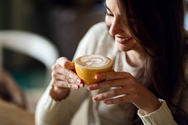 mulher feliz desfrutando em xícara de café fresco. - latté cafe froth art cup - fotografias e filmes do acervo