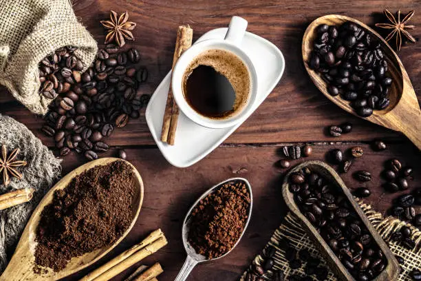 Photo of Espresso coffee cup on vintage table and assortment of grinded and roasted coffee beans