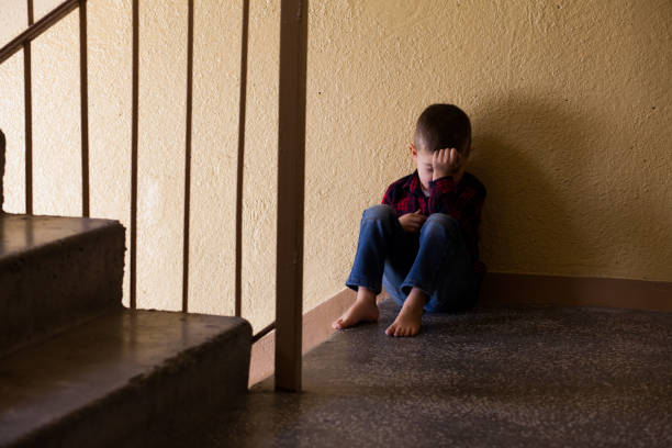 distraught boy in stairwell - displeased child abandoned child abuse imagens e fotografias de stock