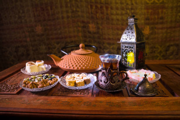 istock Arabian tea in glass with eastern snacks on vintage wooden surface. Eastern tea concept. Low light lounge interior with carpet. Empty space. 1128657131
