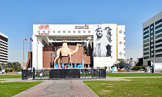 Dubai, United Arab Emirates – February 13, 2018: Exterior view of the Municipality Building on the Creek side with a camel statue in front.