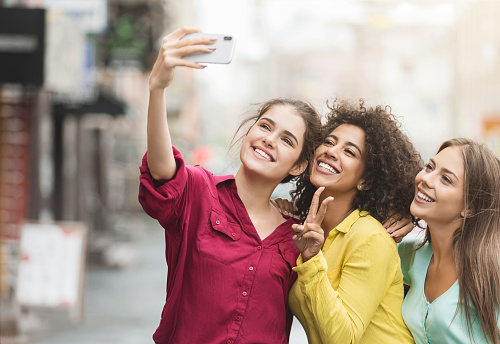 Diverse happy women taking selfie, walking in the city and enjoying time together