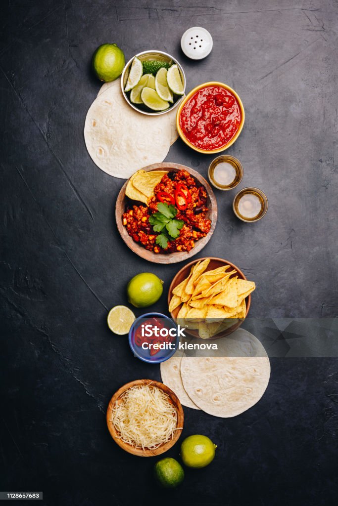 Concept of Mexican food, flat lay Concept of Mexican food (corn tortillas, nachos, salsa, avocado, limes, cheese, chili con carne) flat lay Ingredient Stock Photo