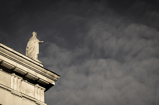 Statue of a priest reaching out to make a blessing on the city beyond, standing on the roof of a neoclassical church.  St Mary's Pro Cathedral (Roman Catholic), Dublin, Ireland.  The church is located in Dublin's city centre.  It was built in 1825 to a greek revival / neoclassical design by John Sweetman.