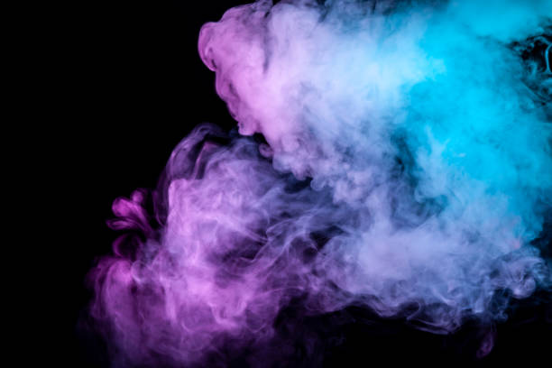 istock Translucent, thick smoke, illuminated by light against a dark background, divided into three colors: blue, green and purple, burns out, evaporating from a steam of vape. 1128658448