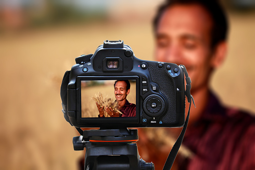 Young farmer of Indian ethnicity holding wheat in his hand and he is looking so happy.