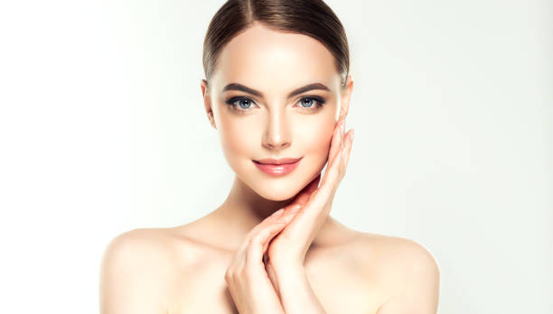 gorgeous, young woman with clean, fresh skin is touching own face.  light smile on the perfect face. cosmetology. - ayurveda massaging spa treatment wellbeing imagens e fotografias de stock