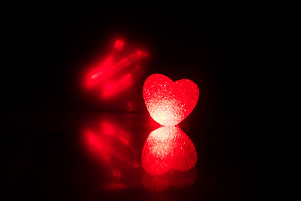 istock Blurred neon heart icon on a dark background. Copy space with red bright colorful heart on black background 1128661830