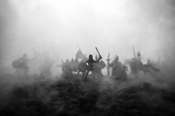 istock Medieval battle scene with cavalry and infantry. Silhouettes of figures as separate objects, fight between warriors on sunset foggy background. Selective focus 1128663720