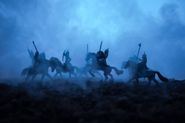 istock Medieval battle scene with cavalry and infantry. Silhouettes of figures as separate objects, fight between warriors on sunset foggy background. Selective focus 1128663729