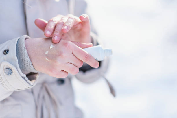 ผู้หญิงใช้ครีมทามือบนมือแห้ง - female hand with tube of the body cream ภาพสต็อก ภาพถ่ายและรูปภาพปลอดค่าลิขสิทธิ์