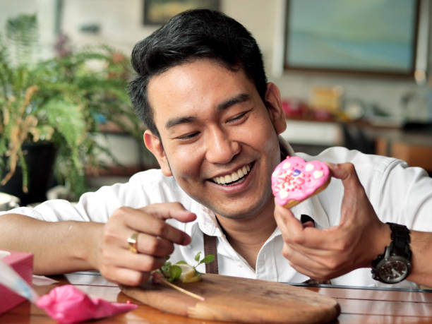 istock Happy Asian man decorating valentine cookie at home. 1128664755