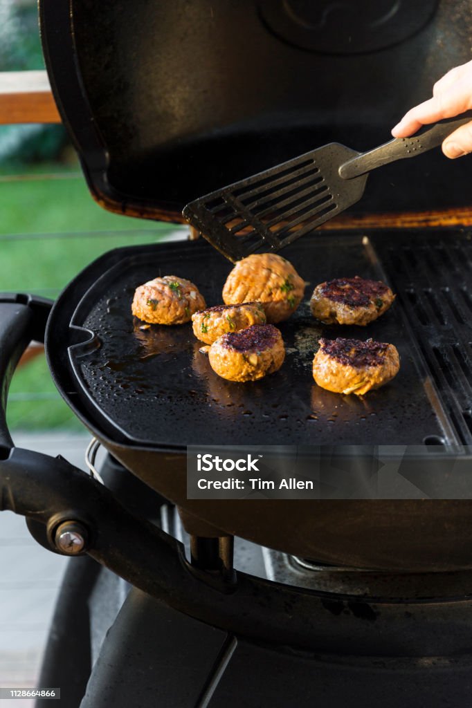 Flipping Homemade Burgers Over To Cook Over Side Flipping homemade burgers over to cook over side. Adult Stock Photo