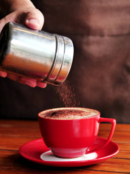 istock Hand sprinkles chocolate powder on drink in red cup. 1128665688