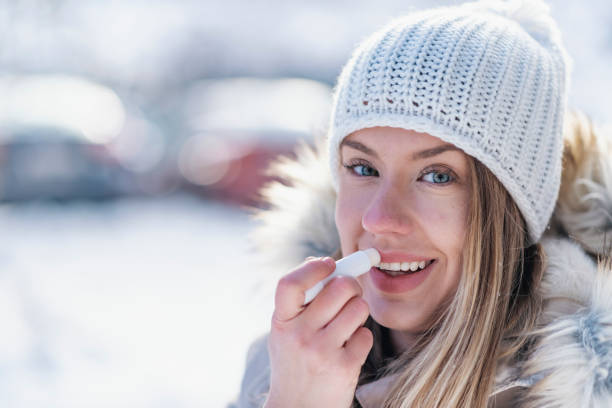 istock Woman applying lip balsam while walk on a wintry day. 1128665734