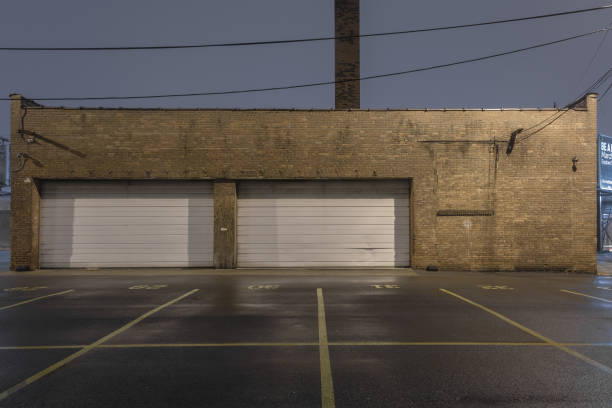 istock Vintage brick industrial building with twin white roll up doors and parking spaces 1128667569