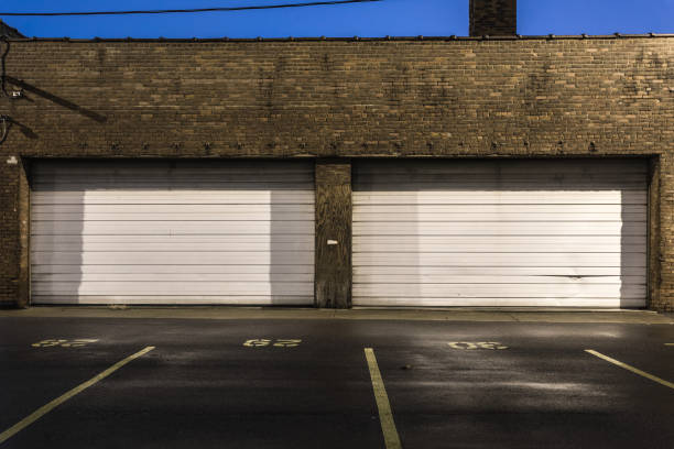 istock Two white roll up doors of vintage brick industrial building with parking spaces 1128668091