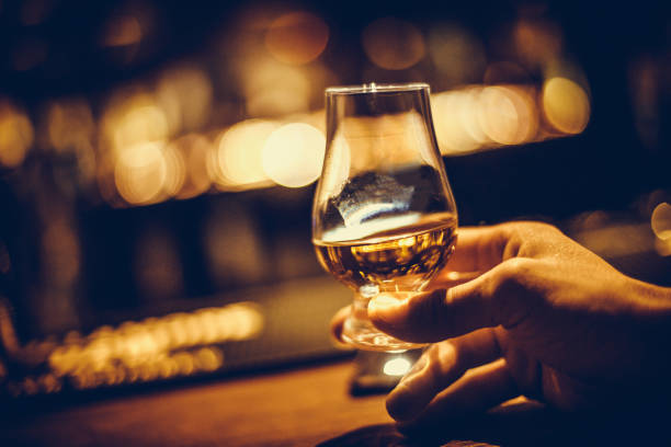 hand holding a glencairn single malt whisky glass - tasting imagens e fotografias de stock