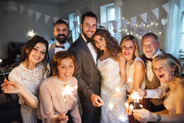 istock A young bride, groom and guests posing for a photograph on a wedding reception. 1128671761