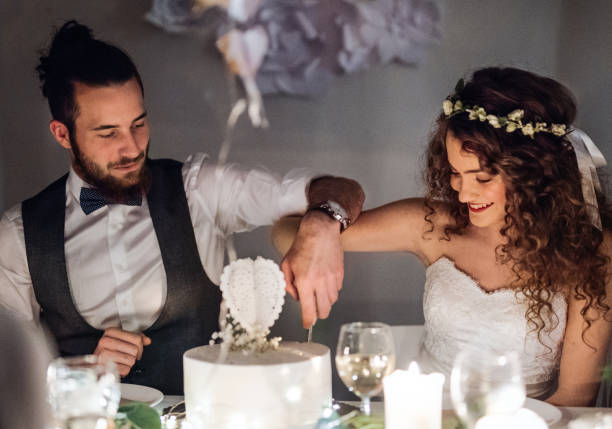 istock A young couple sitting at a table on a wedding, cutting a cake. 1128672003