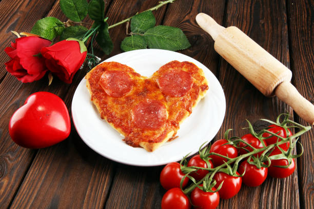 istock Valentines day pizza in heart shape on dark rustic wooden background. 1128675428
