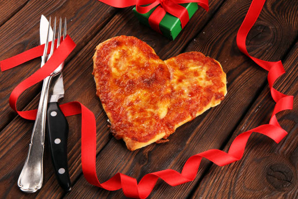 istock Valentines day pizza in heart shape on dark rustic wooden background. 1128675986
