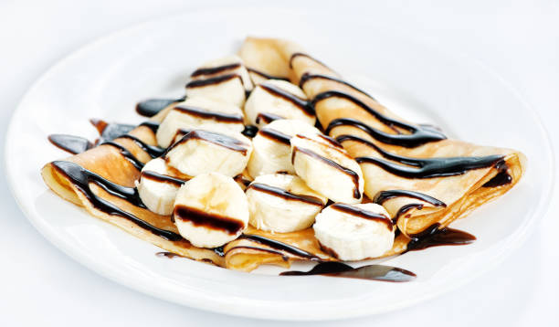 istock Thin delicious pancake with banana and chocolate on white 1128676513